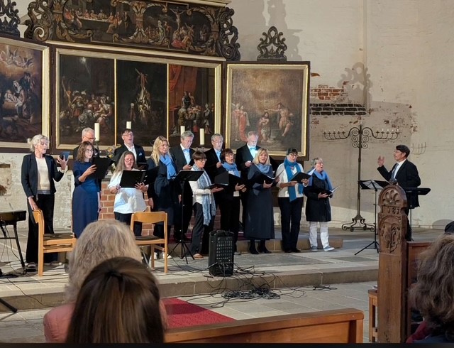 Eine Chorgruppe steht in der Heilig-Geist-Kirche in Wismar vor dem Altar und singt.